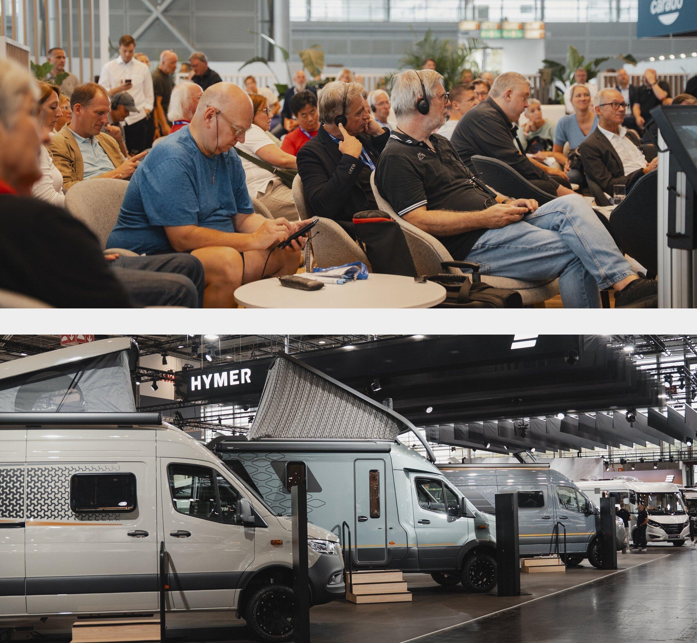 HYMER press conference at Caravan Salon 2026: listeners following the interpretation on headphones, below the HYMER exhibition stand with motorhomes